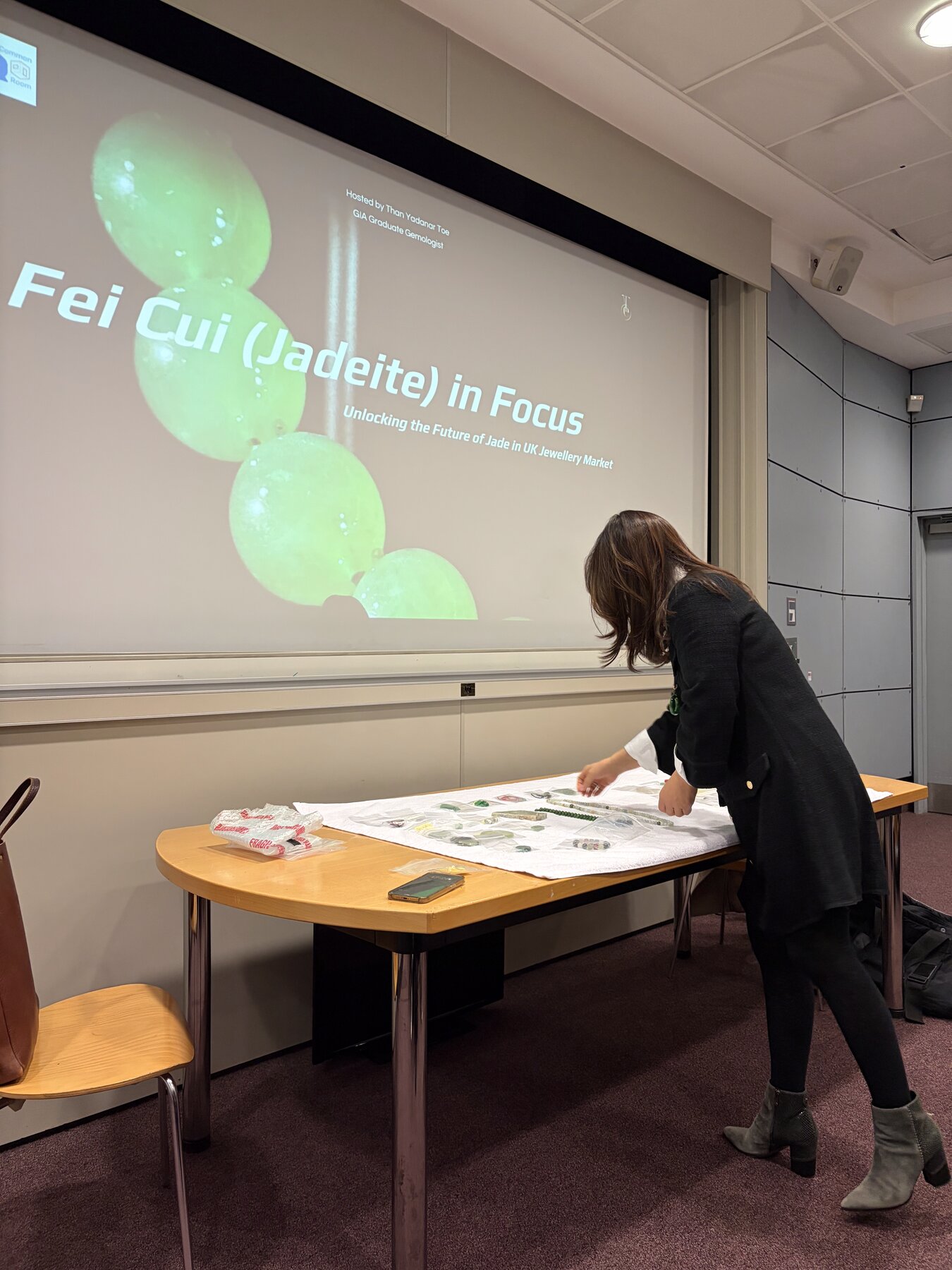 Kehan Li seated at the lecture table with the Feicui (Jadeite) in Focus title slide behind her.